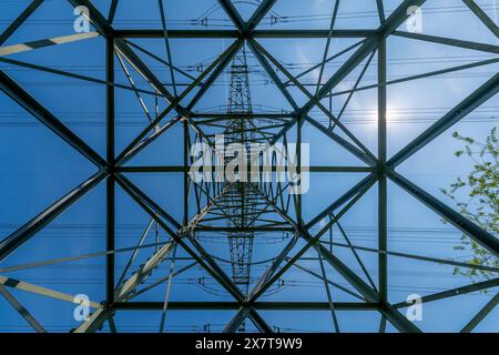 Osserva la geometria disciplinata di una torre ad alta tensione come si vede dalla vista di un verme, un'affascinante miscela di forza e struttura in un perfetto harmo Foto Stock