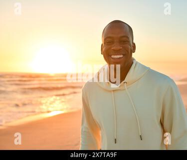 Ritratto di giovane uomo vestito in modo informale che guarda l'alba al mattino sulla spiaggia e sul mare in Sud Africa Foto Stock