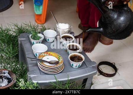 I chicchi di caffè appena tostati, il mortaio e il pestello con jebena e il fumo di incenso creano una tradizionale preparazione per la cerimonia del caffè etiope Foto Stock