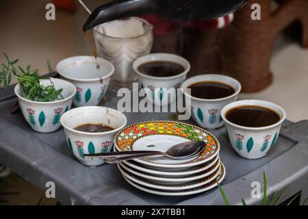 I chicchi di caffè appena tostati, il mortaio e il pestello con jebena e il fumo di incenso creano una tradizionale preparazione per la cerimonia del caffè etiope Foto Stock