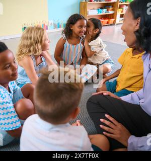Lezioni di scuola primaria o elementare multiculturale con studenti che si sussurrano tra loro Foto Stock