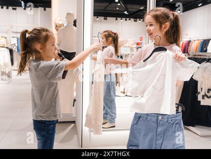 Due ragazze che fanno acquisti di vestiti in un negozio illuminato durante il giorno Foto Stock