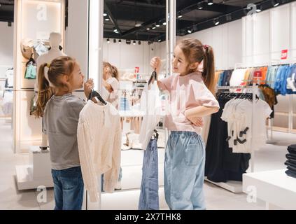 Due ragazze che guardano i vestiti in un negozio di abbigliamento Foto Stock