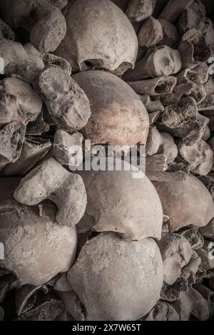 teschi e ossa impilati in una tomba Foto Stock