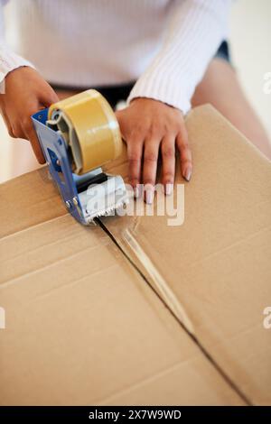 Scatola, mani e donna con nastro adesivo a casa per il movimento, cartone e imballaggio per immobili o immobili. Primo piano, persona e ragazza con adesivo, pacco Foto Stock