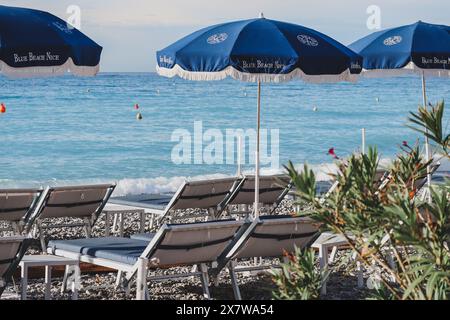 Nizza, Francia - 29.09.2022 : ombrelloni aperti della Spiaggia Blu Nizza e sedie a sdraio sulla riva del Mediterraneo Foto Stock