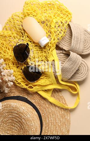 Borsa a cordoncino e diversi accessori da spiaggia sullo sfondo beige, vista dall'alto Foto Stock