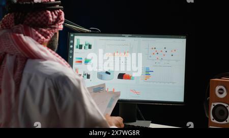 Uomo d'affari concentrato che controlla il set di dati statistici analitici mentre lavora in remoto negli uffici degli appartamenti. Il dirigente aziendale ottimizza gli indicatori chiave di prestazione, primo piano Foto Stock