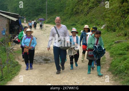 Un tizio caucasico viene molestato da donne locali per comprare souvenir, Cat Cat Village, Sapa, Lao Cai, Vietnam. Foto Stock