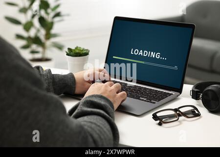 Schermata di caricamento con visualizzazione dell'avanzamento. Uomo che lavora al portatile a un tavolo all'interno, primo piano Foto Stock
