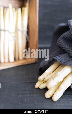 Asparagi bianchi su sfondo scuro, distesi e impilati in una cassa di legno Foto Stock