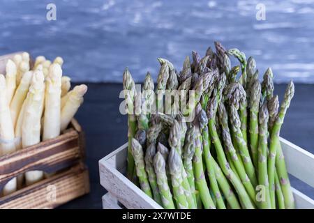 Asparagi bianchi e verdi in casse di legno su sfondo chiaro e scuro Foto Stock