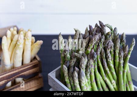 Steli di asparagi bianchi e verdi in casse di legno su sfondo chiaro e scuro Foto Stock