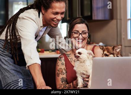 Felice, coppia e laptop per rilassarsi con i cani in casa in cucina navigare su Internet per lo shopping online cura degli animali domestici. Sorridi, uomo e donna con animali per Foto Stock