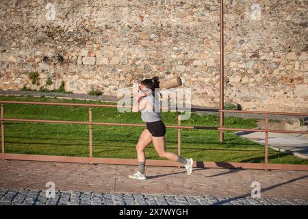 Merida, Spagna - 18 maggio 2024: FarinatoRace Merida 2024. Donna che porta un grosso tronco sulla spalla Foto Stock