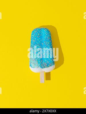 Gelato glassato blu a base di papavero su sfondo giallo. Concetto estivo minimalista. Gelati. Posizione piatta. Foto Stock