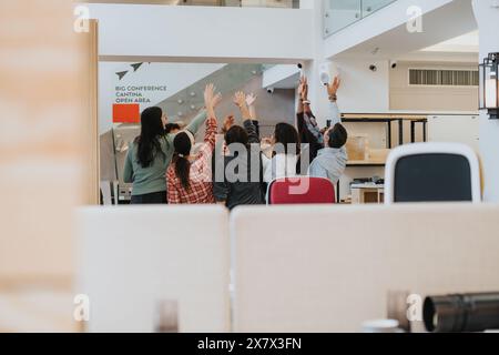 Team entusiasta che celebra il successo in un ambiente di ufficio moderno. Foto Stock