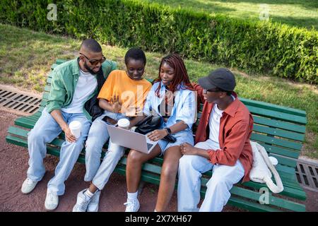 Quattro studenti afroamericani ragazze e ragazzi che guardano il laptop dello schermo durante una pausa caffè all'aperto. Foto Stock