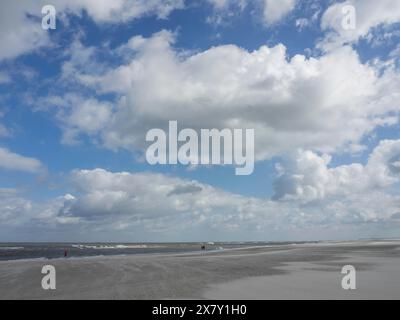 Spiaggia luminosa sotto un cielo leggermente nuvoloso con vista sul mare calmo, onde su una spiaggia, giornata di sole con nuvole nel cielo sul mare, Spiekeroog, GER Foto Stock