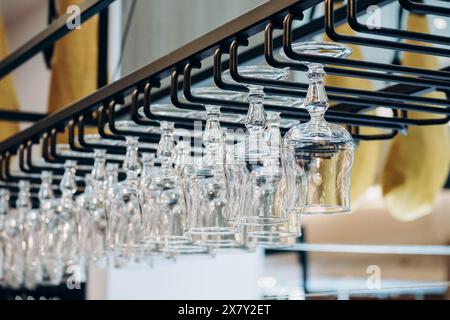 Vino e bicchieri da cocktail appesi a testa in giù in un bar Foto Stock