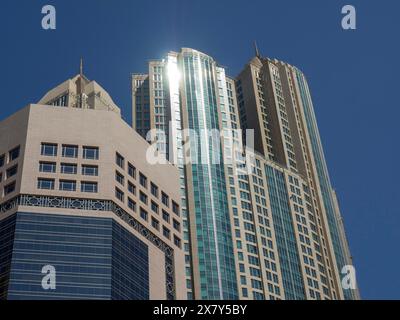 Torreggianti edifici in vetro con sorprendenti dettagli architettonici sotto un cielo blu, moderni grattacieli con facciate in vetro e molte finestre, Abu dhabi, Arab Foto Stock