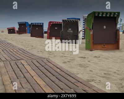 Sedie a sdraio e un molo di legno sulla spiaggia con un cielo nuvoloso e una vista sul mare, sedie a sdraio e tende da spiaggia sul mare con un cielo nuvoloso, tavola Foto Stock