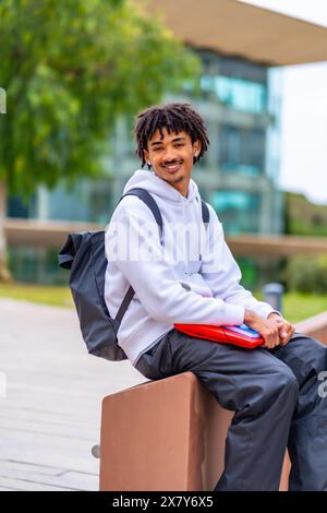 Vista laterale verticale di uno studente afroamericano sorridente con dreadlock che ti aspettano seduti fuori dall'università Foto Stock