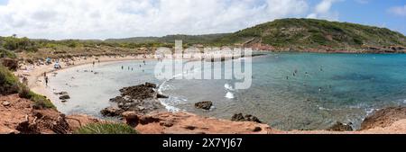 Ampia vista panoramica della spiaggia di es Tancats e Algaiarens a Minorca, circondata da uno spazio naturale con persone che si godono le acque cristalline Foto Stock