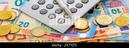 Eurowährung und Geldscheine Ein Taschenrechner und Euromünzen liegen auf Euro Banknoten *** banconote e banconote in euro Una calcolatrice tascabile e euro c Foto Stock
