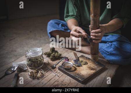 Un uomo prepara marijuana su un tagliere per fumare, persona che fuma droga, tossicodipendenza, tossicodipendenza e sintomi di astinenza. DrugsInte Foto Stock