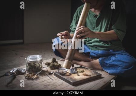 Un uomo prepara marijuana su un tagliere per fumare, persona che fuma droga, tossicodipendenza, tossicodipendenza e sintomi di astinenza. DrugsInte Foto Stock