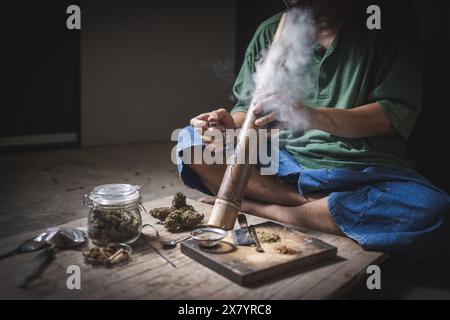 Un uomo prepara marijuana su un tagliere per fumare, persona che fuma droga, tossicodipendenza, tossicodipendenza e sintomi di astinenza. DrugsInte Foto Stock