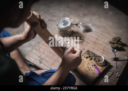 Un uomo prepara marijuana su un tagliere per fumare, persona che fuma droga, tossicodipendenza, tossicodipendenza e sintomi di astinenza. DrugsInte Foto Stock