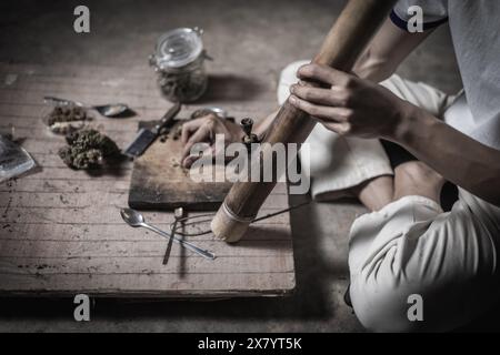 Un uomo prepara marijuana su un tagliere per fumare, persona che fuma droga, tossicodipendenza, tossicodipendenza e sintomi di astinenza. DrugsInte Foto Stock