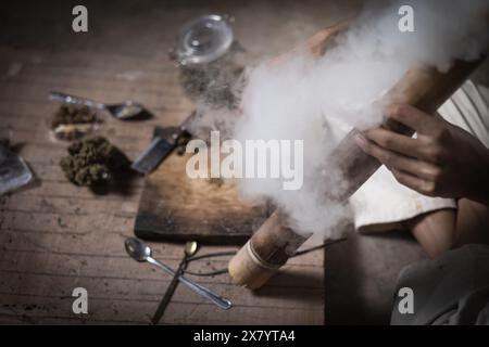 Un uomo prepara marijuana su un tagliere per fumare, persona che fuma droga, tossicodipendenza, tossicodipendenza e sintomi di astinenza. DrugsInte Foto Stock