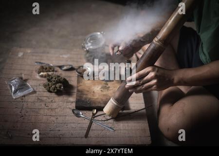 Un uomo prepara marijuana su un tagliere per fumare, persona che fuma droga, tossicodipendenza, tossicodipendenza e sintomi di astinenza. DrugsInte Foto Stock