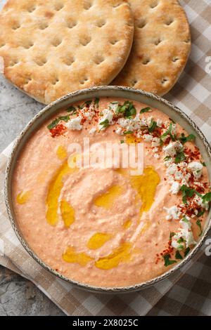 Htipiti o Tirokafteri una deliziosa feta greca e peperoncino rosso arrosto immergono il primo piano sulla ciotola sul tavolo. Vista dall'alto verticale Foto Stock