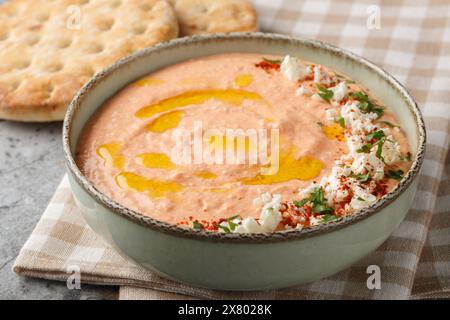 Pasta di formaggio Tirokafteri feta a base di peperoni arrostiti, yogurt greco, olio di olive e aglio in primo piano sulla ciotola sul tavolo. Orizzontale Foto Stock