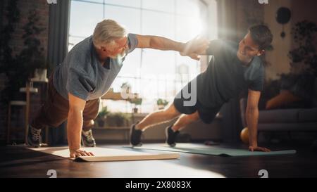 Uomo di mezza età che esercita a casa con Personal Trainer. Uomini anziani che rafforzano i muscoli del corpo con allenamento Push-UPS. Figlio che si allena con il padre sportivo, motivandosi a vicenda dando un High Five. Foto Stock