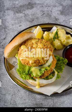 Doppio hamburger di pesce con insalata di patate su un piatto di metallo Foto Stock