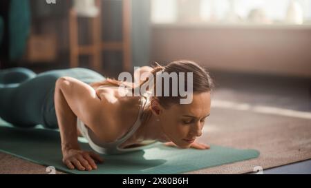 Primo piano dell'atletica femminile che si allena, si allena e fa yoga al mattino nella sua luminosa stanza soleggiata a casa. Bella donna in abiti sportivi che fa diverse pose Asana sul tappetino. Foto Stock
