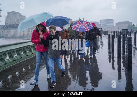 Westminster, Londra, Regno Unito. 22 maggio 2024. I pedoni sfidano la pioggia mentre attraversano il ponte di Westminster . È stato emesso un avviso meteorologico per inondazioni e temporali a Londra e nel sud dell'Inghilterra credito: amer ghazzal/Alamy Live News Foto Stock