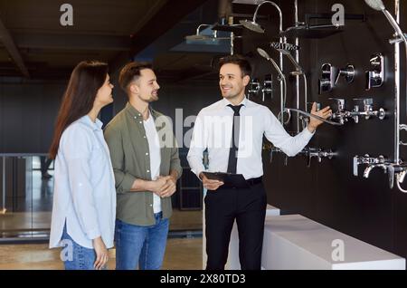 La coppia ha scelto rubinetti e doccia per il bagno con il venditore nel negozio di articoli idraulici. Foto Stock