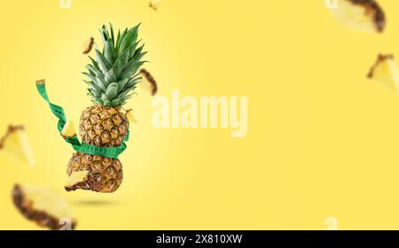 Ananas serrato con nastro metrico su sfondo giallo, spazio di copia. Concetto di dimagrimento. Foto Stock