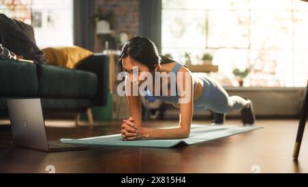 Allenarsi donna, guardare Trainer su un notebook, tramite video tutorial online mentre si pratica la formazione virtuale a casa. Atletica che utilizza l'abbonamento fitness ai servizi di streaming. Colpo al suolo basso Foto Stock