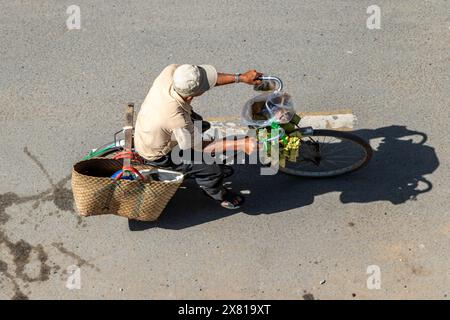 Un ciclista cavalca con una borsa e un gruppo di riso Sticky al vapore con Banana, Saigon City, Vietnam Foto Stock
