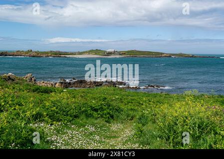 Vista da l'Eree Headland Guernsey all'Isola di Lihou con accesso attraverso una strada rialzata con la bassa marea, una riserva naturale di isolotti spazzati dal vento, il punto più westerley Foto Stock