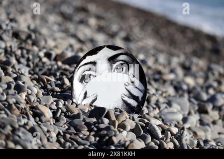 Piatto Fornasetti sulla spiaggia di ciottoli, il volto appartiene alla cantante lirica italiana Lina Cavalieri Foto Stock