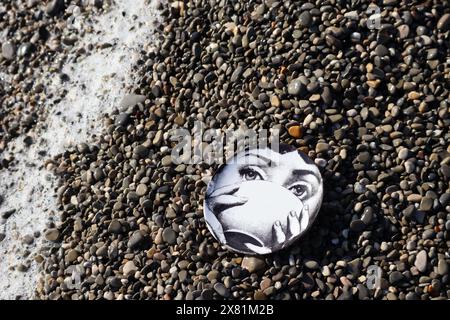 Piatto Fornasetti sulla spiaggia di ciottoli, il volto appartiene alla cantante lirica italiana Lina Cavalieri Foto Stock