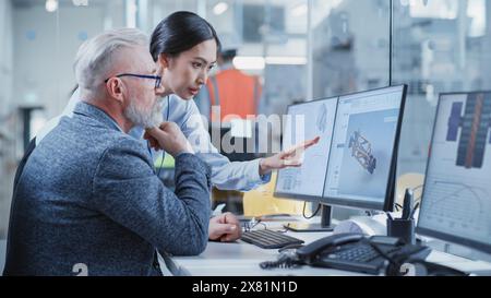 Stabilimento per uffici: Ingegneri industriali che redigono progetti di parti di macchine per l'industria pesante su un software CAD per computer. Asian Female Technician parla del lavoro con Middle Aged Designer. Foto Stock